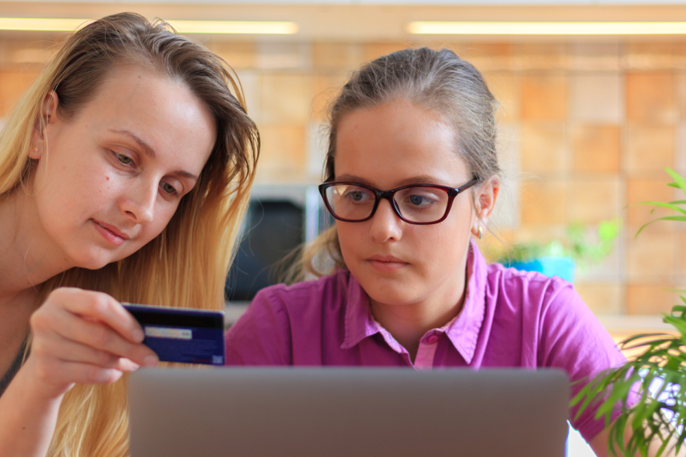 Parent and teen using credit card and laptop.